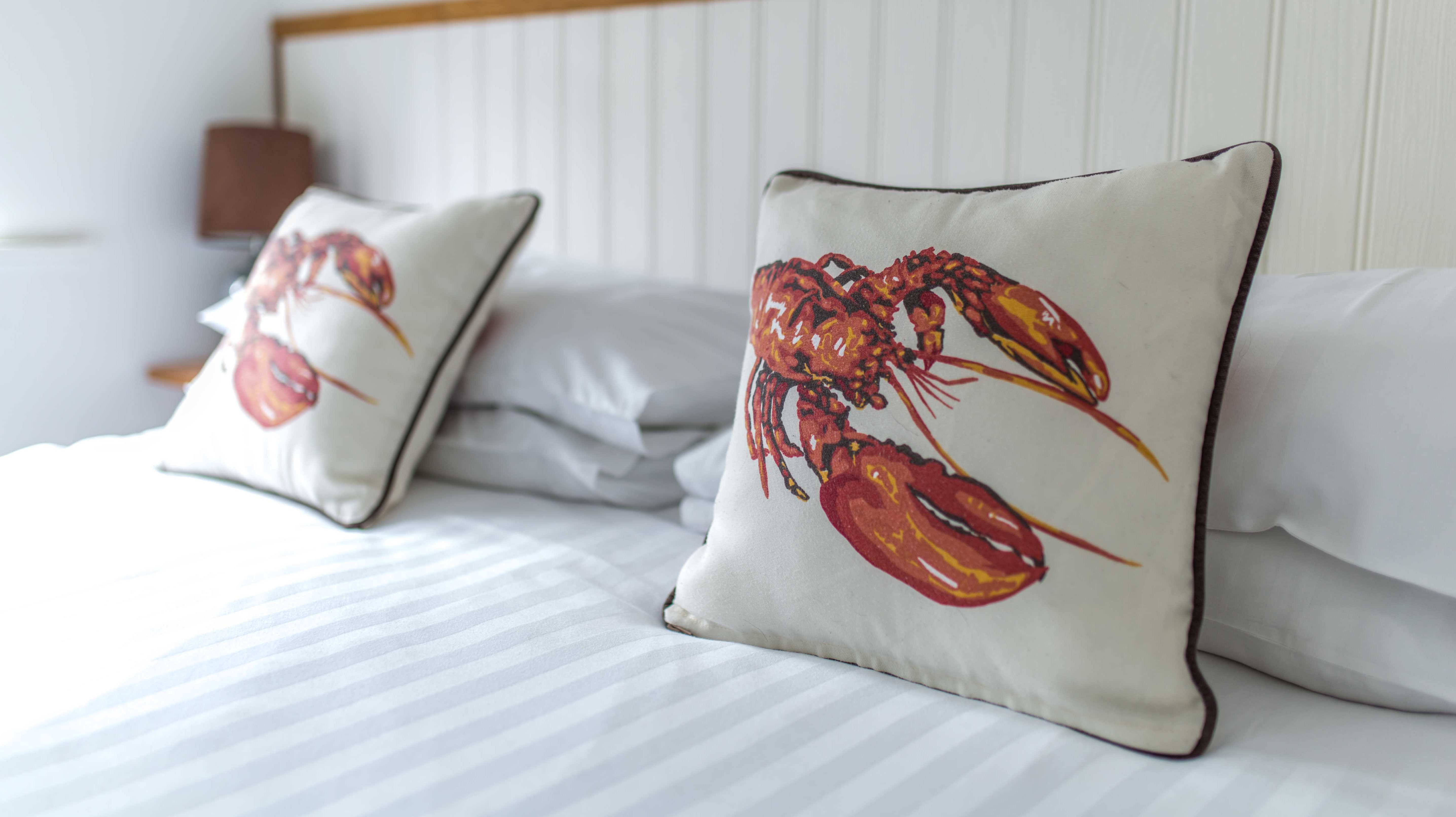 Lobster cushions on the bed at Rock Lobster holiday cottage.